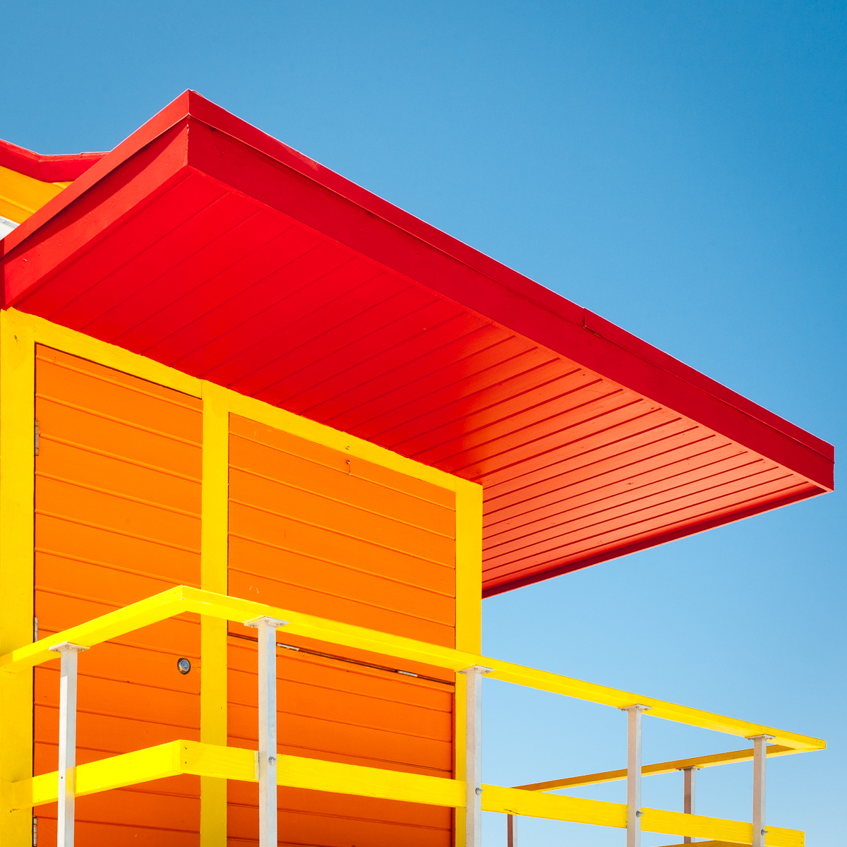 Red, orange and yellow South Beach lifeguard stand against a blue sky